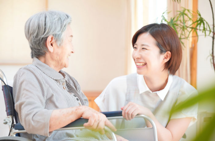 高齢の女性と笑顔で会話する歯科スタッフのイメージ